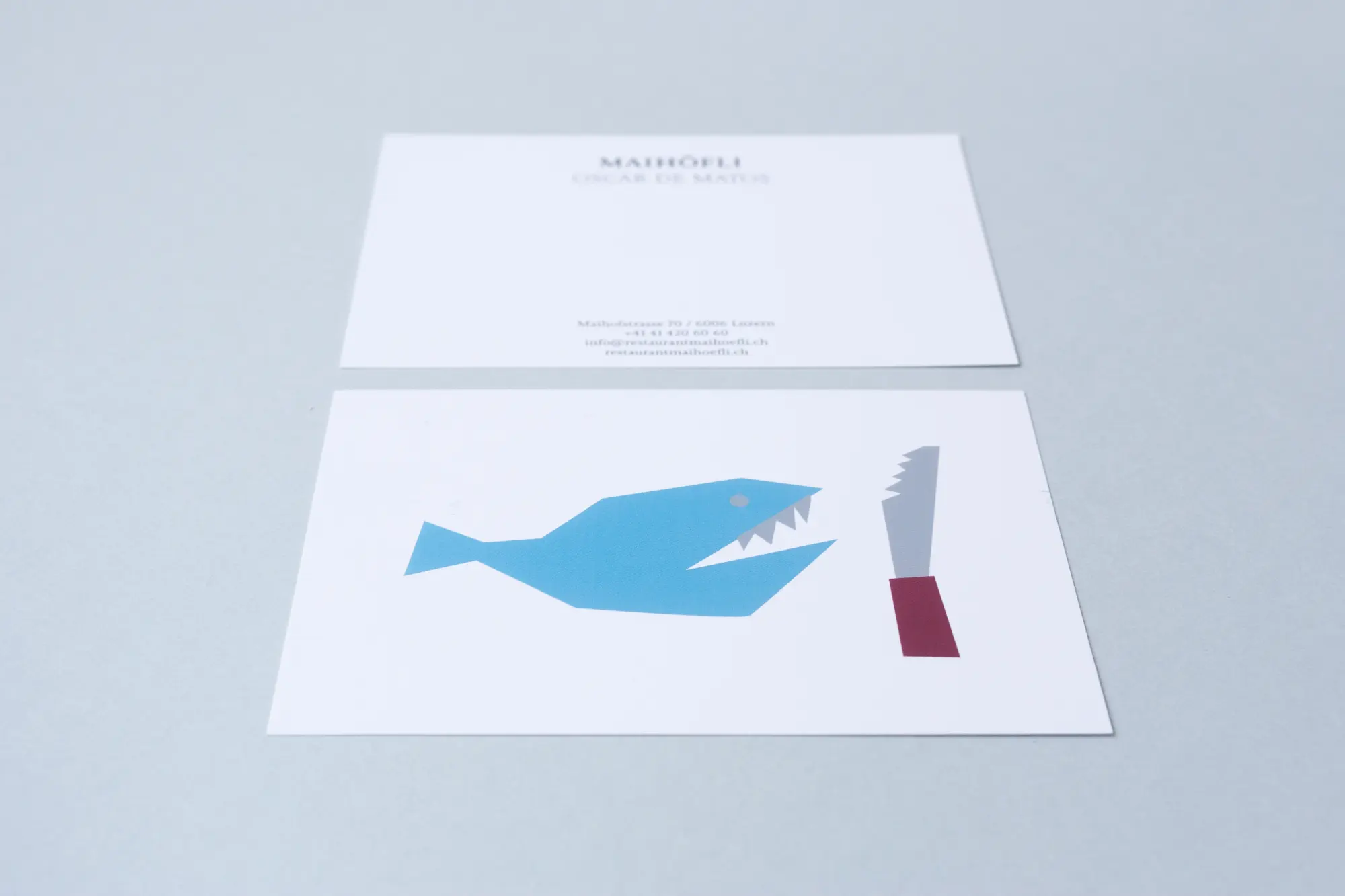 Postkarte 'Maihöfli' des Restaurants von Oscar de Matos mit illustriertem Fisch- und Messermotiv im Corporate Design.